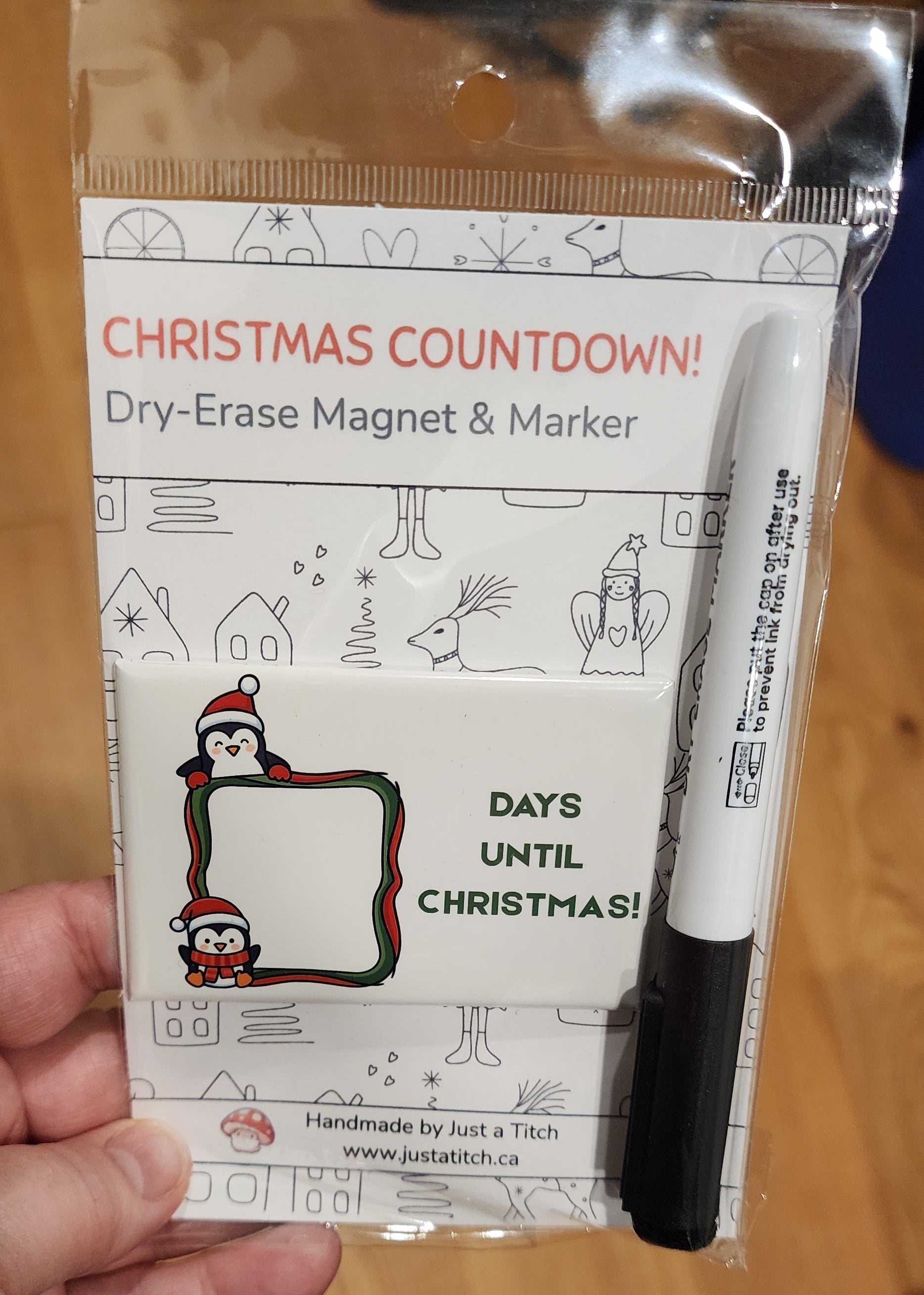 Christmas countdown magnet and marker with packaging held by a hand on a wooden surface